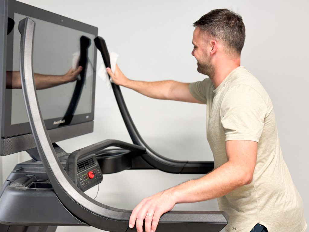 A person cleaning the NordicTrack X32i treadmill.