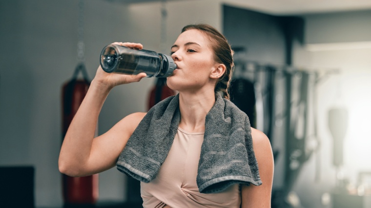 Woman drinking from water bottle while at the gym.