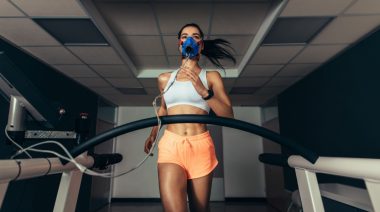 A fit person running on a treadmill with a mask.