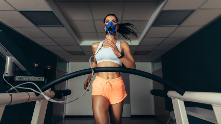 A fit person running on a treadmill with a mask.