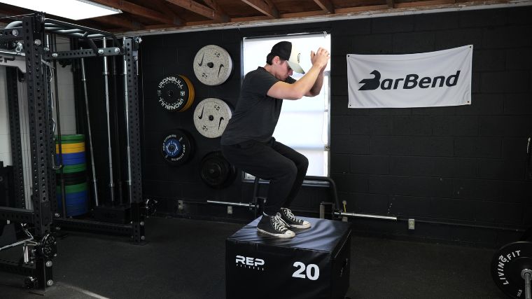 A BarBend tester doing the box jump on a plyo box, as it is one of the best agility training exercises.