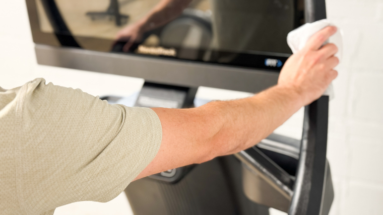 Our tester cleaning their treadmill's side rails and display