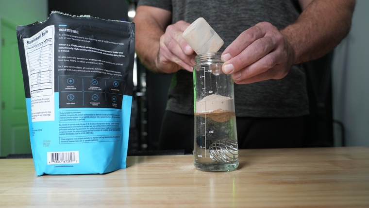 Our tester pours a scoop of Legion Whey into a shaker bottle of water.