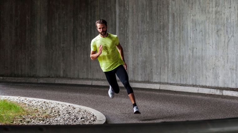 How Does Running Change Your Body: A person wearing sportswear, running on a street in a curve.