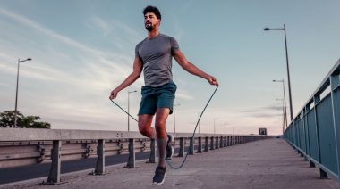 A fit person exercising with a jumping rope outdoors.