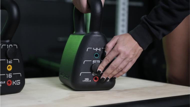 A BarBend tester adjusting the weight on the PowerBlock Adjustable Kettlebell.