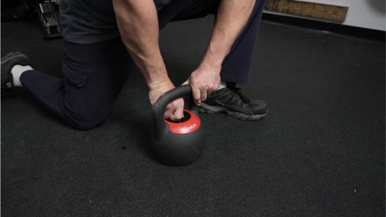 A BarBend tester adjusting the weight on the REP Fitness Adjustable Kettlebell.