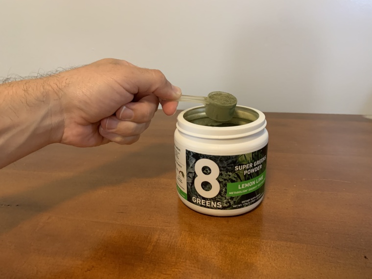 Our tester holds a scoop of 8Greens Super Greens Powder.