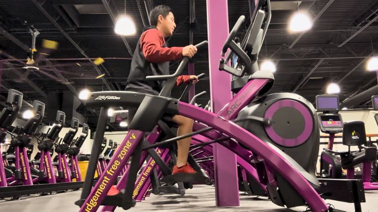 A person on an Arc trainer in a fitness center.