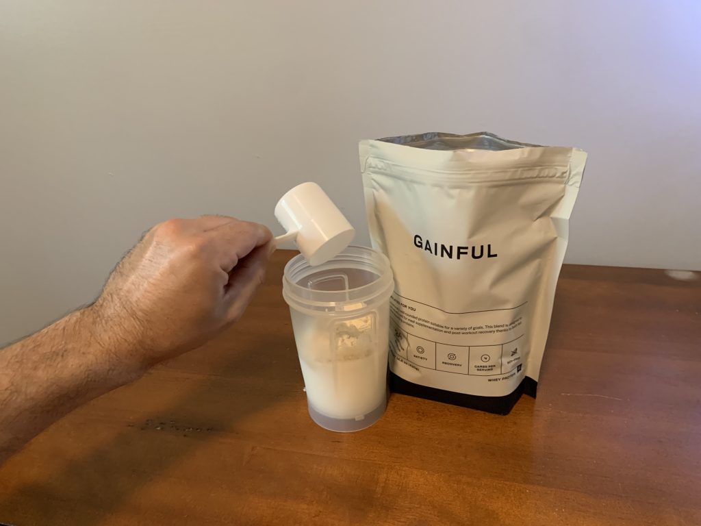 Our testing dumping a scoop of Gainful protein powder over cup