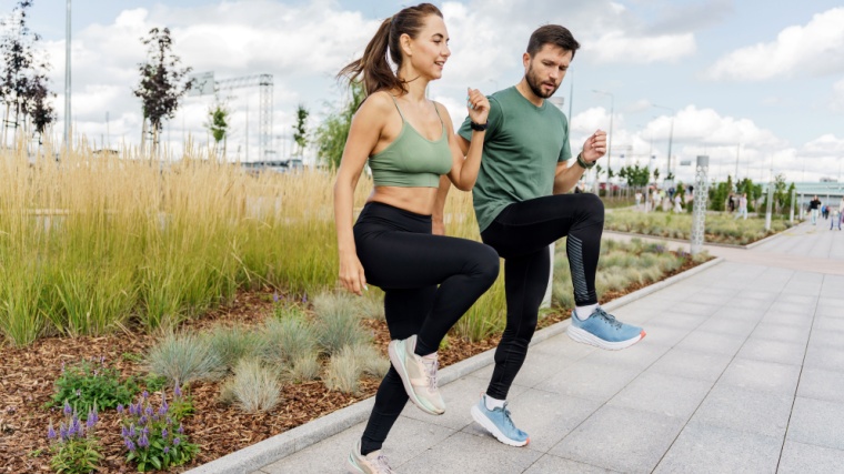 Two fit people performing the high knees exercise.