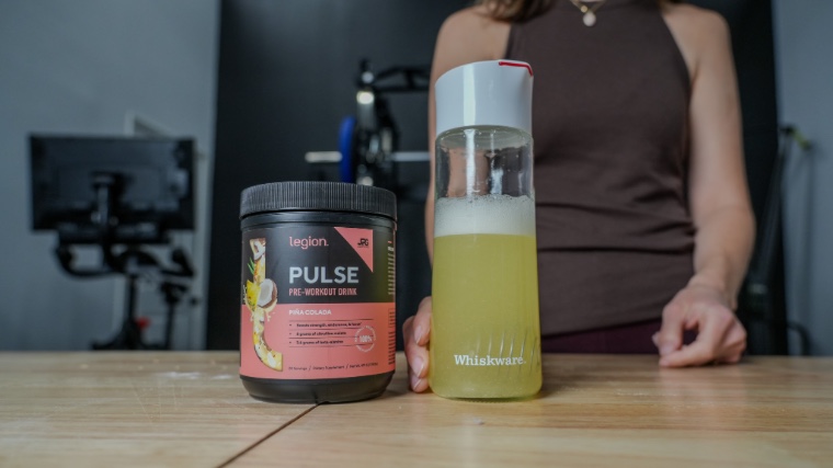 Our tester stands behind a shaker and container of Legion Pulse Pre-Workout.