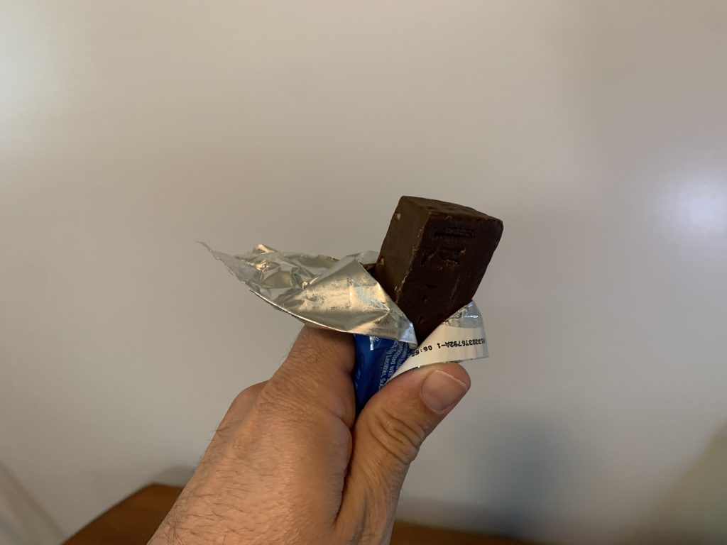 Tester holding an unwrapped protein bar by Pure Protein.