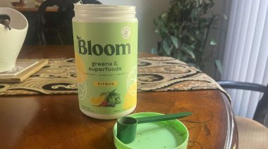 Scoop next to a container of Bloom Greens Powder.
