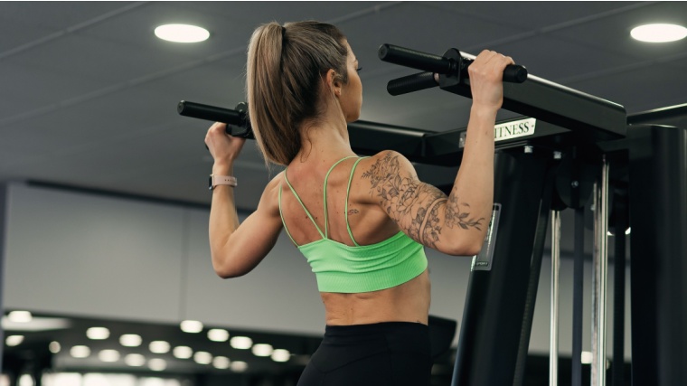 Woman in green tank performs wide-grip pull-up