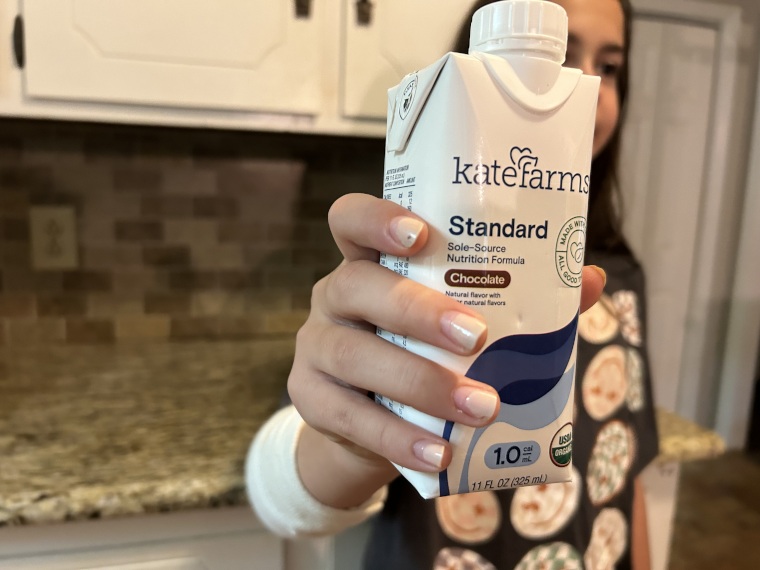 A kid holding up a carton of Kate Farms Pediatric Standard