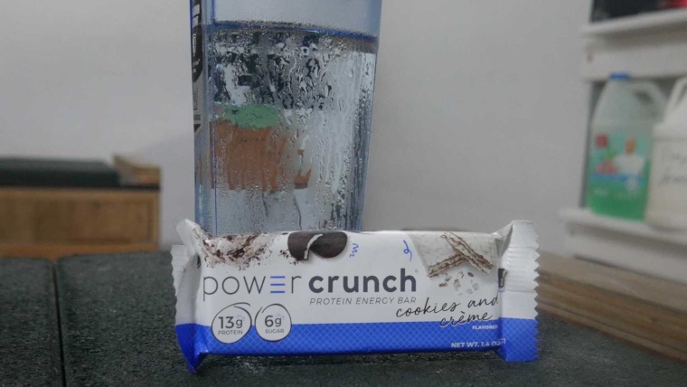 A Power Crunch Bar leans against a full glass of water