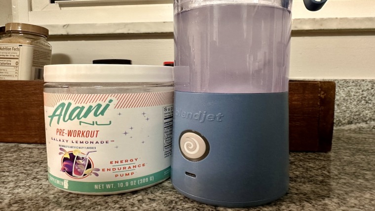 Alani Nu Pre-Workout tub with shake in a blender