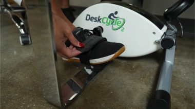 A person strapping their foot on a mini exercise bike.