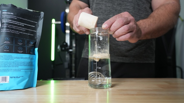 Our tester dumping a scoop of Legion Plant+ Protein Powder into a shaker bottle.