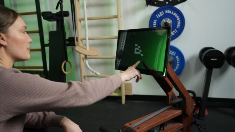 A BarBend tester using the Ergatta Rower's touchscreen.