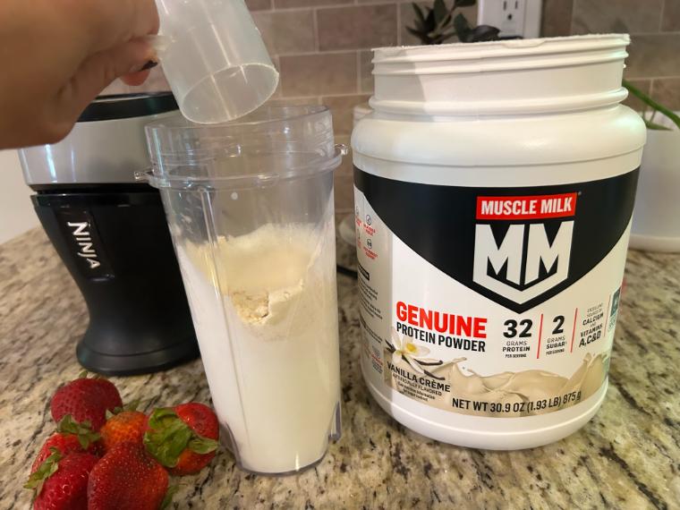 Our tester dumping a scoop of Muscle Milk Genuine Protein Powder in their blender cup.