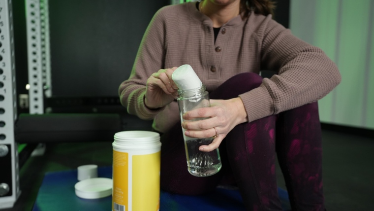 Our tester pours a scoop of MyProtein Clear Whey Isolate into a shaker bottle.