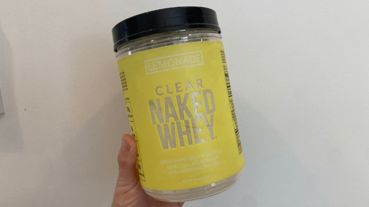 Our tester holds up a container of lemonade-flavored Naked Clear Whey protein powder.