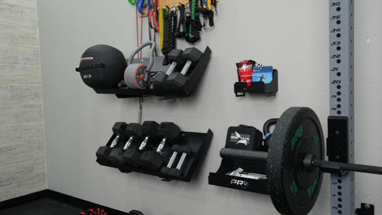 Dumbbells and other equipment loaded on the PRx wall mounted storage containers.