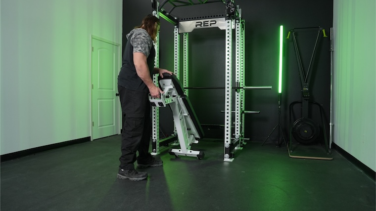 Our tester moving the REP Fitness AB-4100 weight bench into a power rack