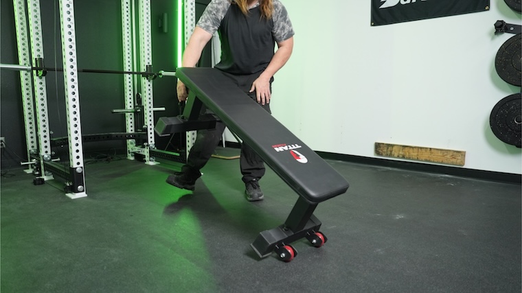 Our tester moving the Titan Fitness Elite Series Single Post Flat Bench into position