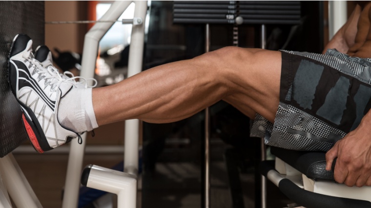 Man performs calf training on leg press station