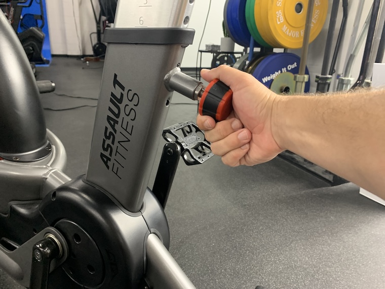 a person adjusting the seat height of the Assault Fitness AirBike Elite.