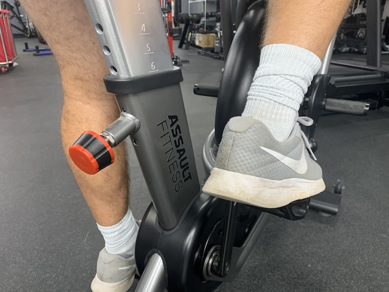 a person's feet on the pedals of the Assault Fitness AirBike Elite.