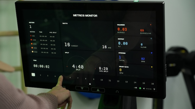 Our tester viewing their training metrics and adjusting resistance levels on the Aviron Strong Rower's 22-inch HD touchscreen display