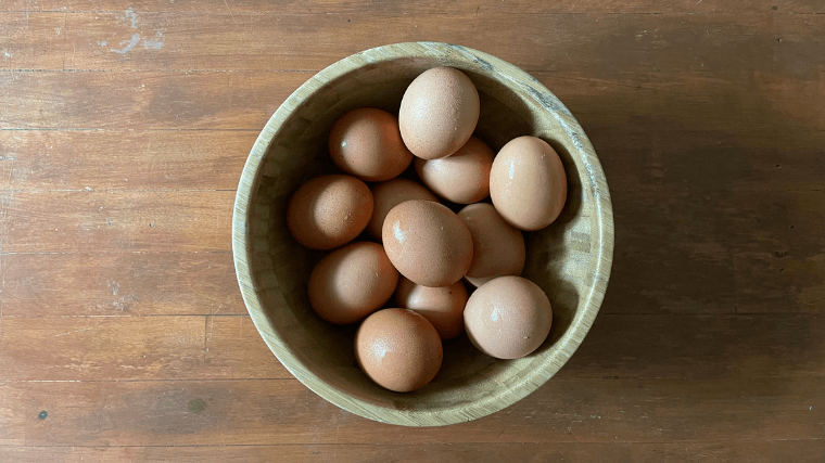 A dozen hard boiled eggs in a wooden bowl.