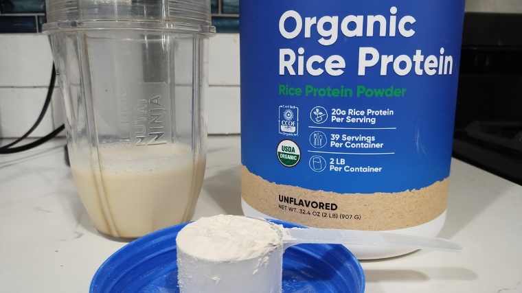 A scoop of Nutricost Organic Rice Protein next to a shake and the container