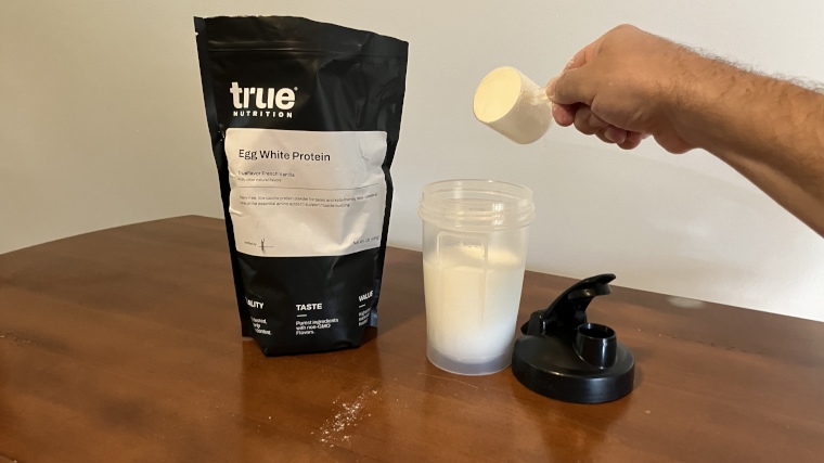 Our tester dumping a scoop of True Nutrition Egg White Protein powder