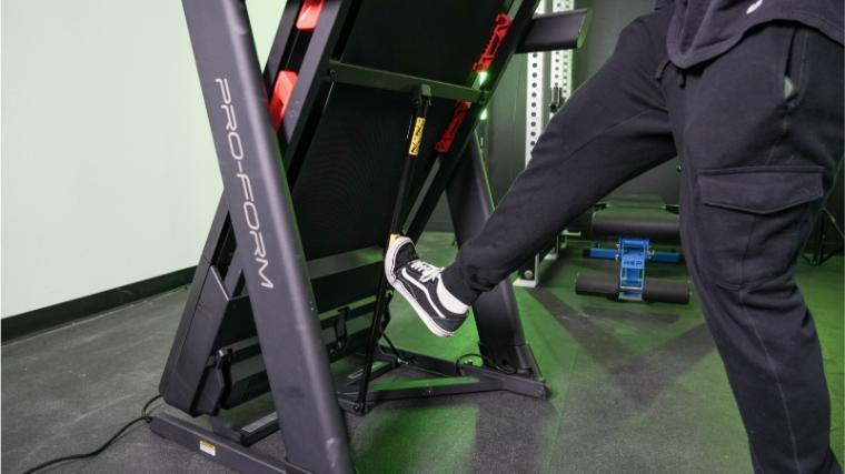 A man taps the underside of the ProForm Carbon TLX with his foot to aid in lowering the treadmill deck back to the ground.