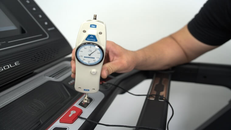 Our tester using a force meter to gauge how much pressure is needed to engage the Sole F80 treadmill's buttons