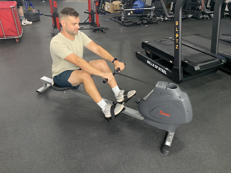 A man using the Sunny Health & Fitness SF-RW5801 Rowing Machine.