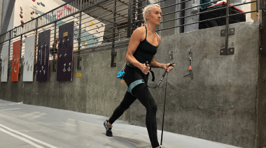 A woman performing lunges with a resistance band at a gym.