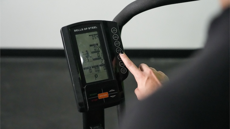 Our tester adjusting the monitor settings on the Bells of Steel Blitz Air Bike 2.0.