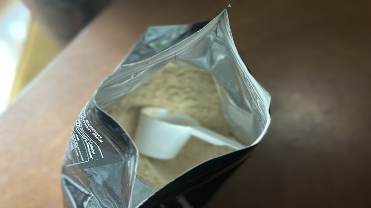 An open container of Huel Black Edition Meal Replacement with the included serving scoop