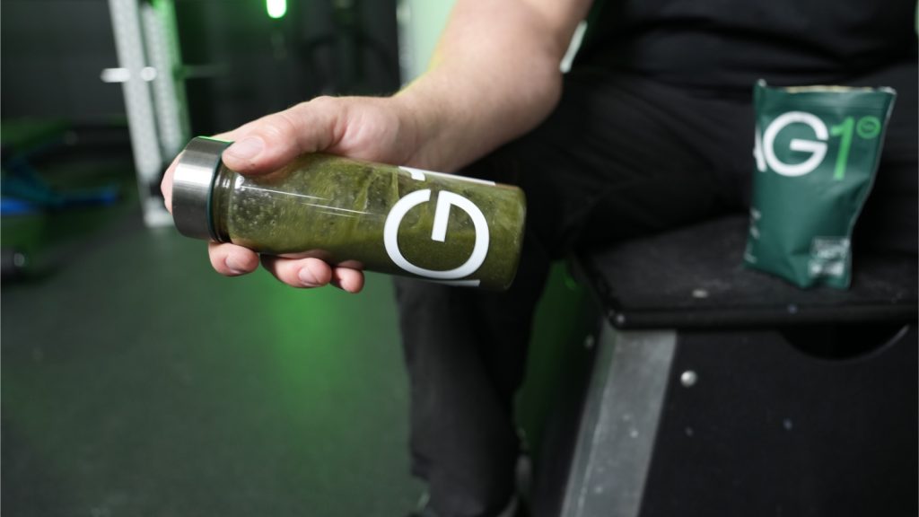 a person holding a bottle of greens powder