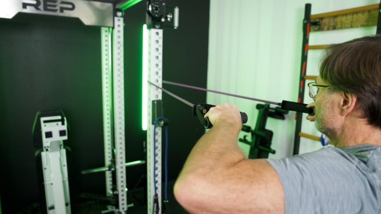 Our tester uses Rogue Tube Bands with a squat rack to do a lat pull back