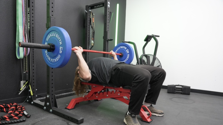 A side view of our tester bench pressing the Synergee Games Cerakote Barbell