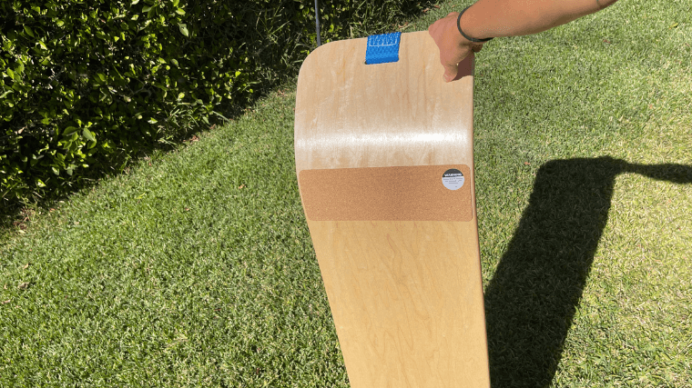 A person holds up the bottom side of the GiBoard which shows a felt pad placed on its base.