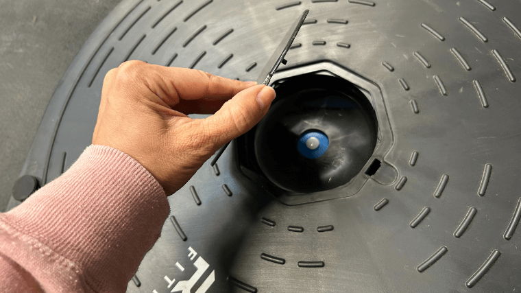 A hand shows the bottom side of the REP Fitness Balance Ball Trainer.