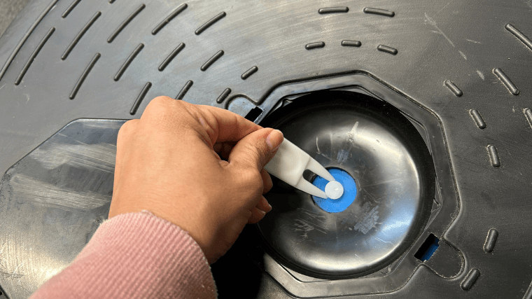 A hand uses a tool to open the inflated ball on the REP Fitness Balance Ball Trainer.